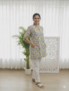blue and yellow floral print tunic top with white trousers.